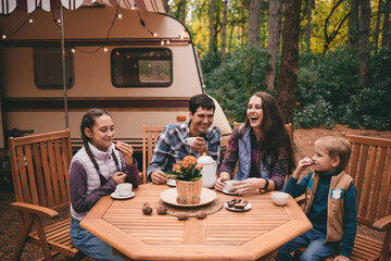 Happy family on a camping trip relaxing in the autumn forest. Camper trailer. Fall season outdoors...