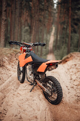 Obraz na płótnie Canvas Orange motocross bike on sand in forest