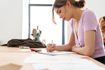 Photo of woman fashion designer making sketches while working at table