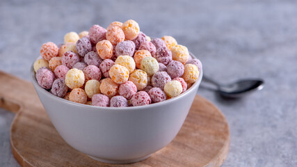 Colorful cereal corn balls mix, fruit flavor bowl sweets on gray cement background, close up, fresh, delicious and healthy breakfast, copy space design concept.