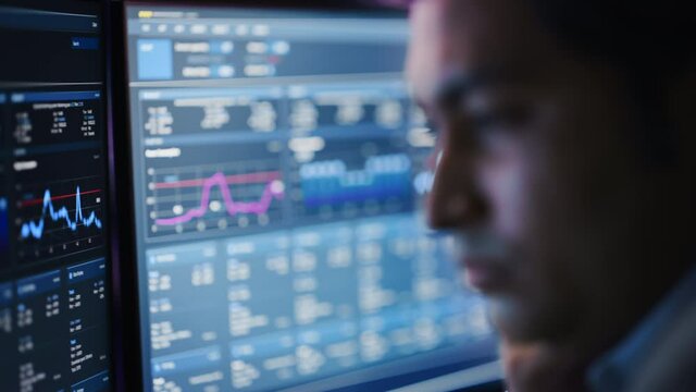 Confident Handsome Man Looks at Monitor Screen with Camera Moving to Computer Screen Showing Data, Infographics, Information, Statistics, Numbers. Businessman Working on Computer in the Office