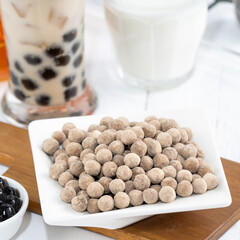 Bubble milk tea with tapioca pearl topping ingredient, famous Taiwanese drink on white wooden table background in drinking glass, close up, copy space