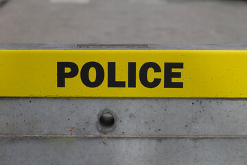 Yellow Police badge, sign, word on cordon - block  reinforcement made of concrete.