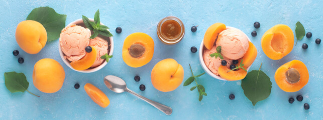 Apricot ice cream with fruits and berries on a blue background, top view, banner.