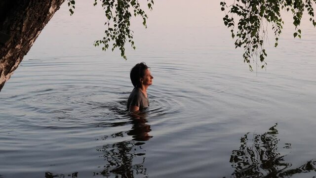 beautiful girl bathes in a lake at sunset