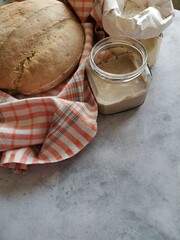 rye sourdough in a glass jar, next to bread and flour
