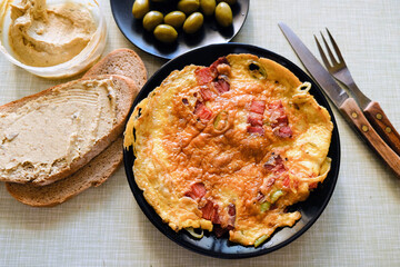 egg omelet with bacon and integral bread with hummus and olives as a salad, closeup