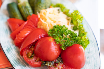 salted and pickled tomatoes, cucumbers and cabbage on plate. appetizer.