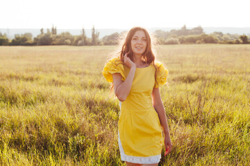 portrait of a beautiful woman in a yellow dress in a field at sunset