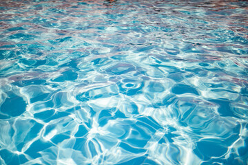 Clear shiny and warm blue water in the pool reflected in it by the rays of the sun in anticipation of tourists. Vacation and travel concept. Advertising space