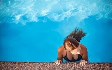 Top view girl teenager swims in the pool in warm clear blue water on sunny summer evening during a...