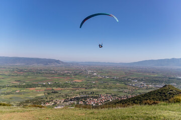 Fototapeta na wymiar Paraglider in the popular area for parachuting on the side of Korylovos in Drama