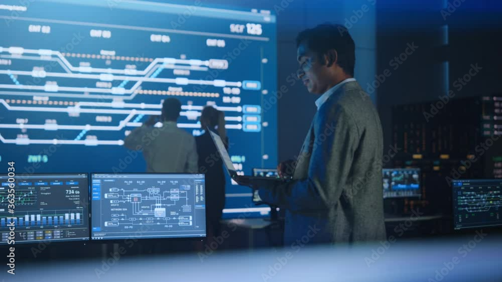 Aufkleber handsome confident male project manager works on a laptop standing in system control room. in backgr