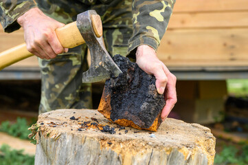 men's hands with an axe clean chaga mushroom birch fungus in the fresh air. step by step