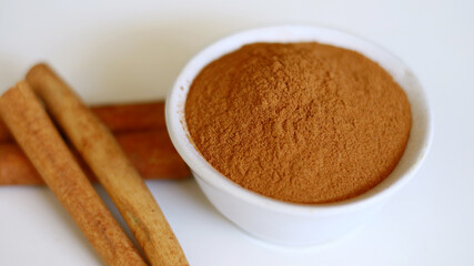 Cinnamon and cinnamon powder on white background.