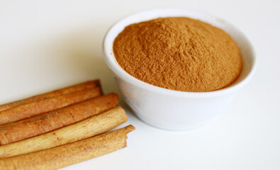 Cinnamon and cinnamon powder on white background.