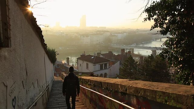 A man walking down the stairs in Croix Rousse, Lyon, during a beautiful sunrise. 