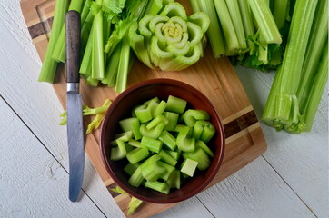 Sliced fresh celery in a clay bowl and Celery stalk on kitchen wooden board