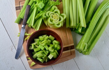 Sliced fresh celery in a clay bowl and Celery stalk on kitchen wooden board