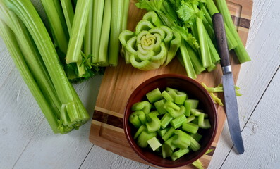 Sliced fresh celery in a clay bowl and Celery stalk on kitchen wooden board