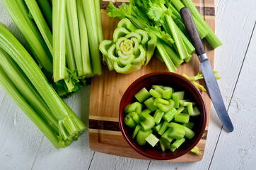 Sliced fresh celery in a clay bowl and Celery stalk on kitchen wooden board