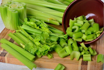 Sliced fresh celery in a clay bowl and Celery stalk on kitchen wooden board
