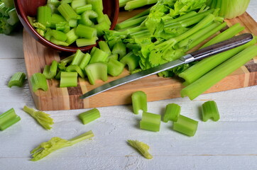 Sliced fresh celery in a clay bowl and Celery stalk on kitchen wooden board