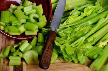 Sliced fresh celery in a clay bowl and Celery stalk on kitchen wooden board