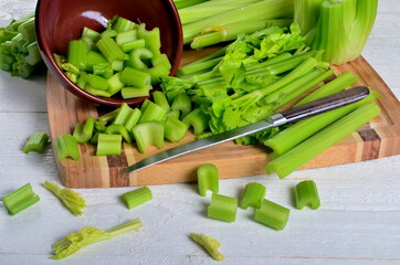 Sliced fresh celery in a clay bowl and Celery stalk on kitchen wooden board