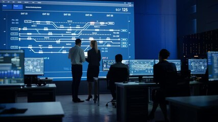 Telecommunications Company System Control and Monitoring Room with Diverse Multicultural Team of Professionals Working on Computers. Big Screen Display Showing Infrastructure Infographics. Back View - Powered by Adobe