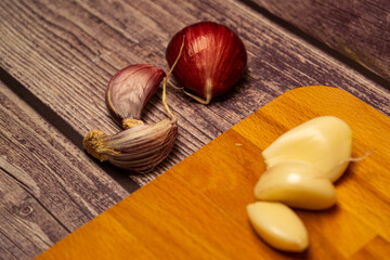 Unpeeled garlic cloves on a wooden background and peeled garlic cloves on a wooden Board. Close up.