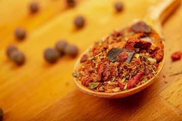 Different ground spices in a wooden spoon on a wooden background. Close up.