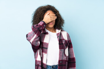 Young African American woman isolated on blue background covering eyes by hands. Do not want to see something