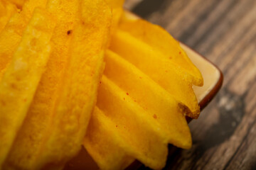 Potato chips with cheese sauce on a wooden background. Close up.