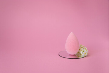 Pink beauty blender with flower isolated on pink background with copy space. Pink blending sponge for makeup. Minimal think. Minimal thing
