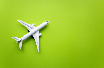 Top view white toy airplane isolated on green background with copy space. Minimal think. Concept of travel vacation. Minimal thing