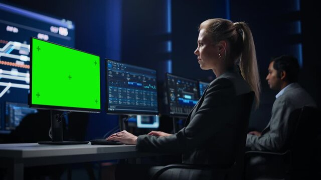 Confident Female Data Scientist Works on Green Chroma Key Screen Computer in Big Infrastructure Control Room. Specialists Use Computers Showing Graphs, Information. Control Room Professional Team