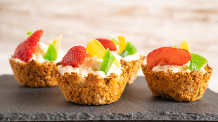 healthy cakes with cottage cheese and fruit in oatmeal baskets on a black board and a white background. cupcakes