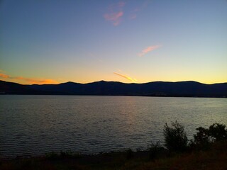 Beautiful sunset on the lake with a clear sky with small yellow clouds.