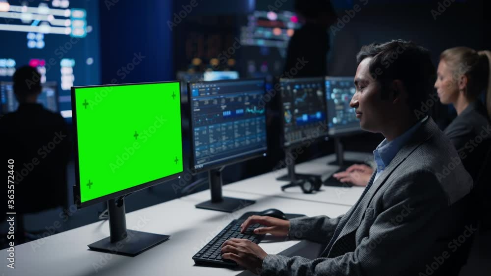 Aufkleber Confident Male Data Scientist Works on Green Chroma Key Screen Computer in Big Infrastructure Control Room. Specialists Use Computers Showing Graphs, Information. Control Room Professional Team