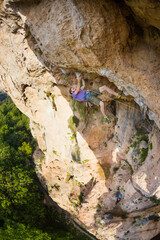 A strong man climbs a beautiful orange rock.