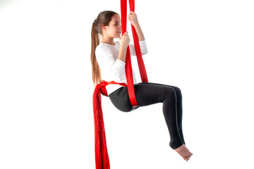 Cute teenager girl in a white sweater and black leggings doing sports acrobatics using a red air ribbon 