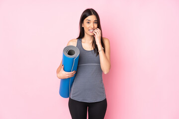 Young caucasian woman with mat isolated on pink background nervous and scared