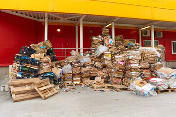 A large pile of cardboard boxes from the goods sold, stored in the back of the supermarket. The concept of urban pollution