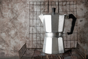 Moka pot italian style coffee maker on old steel grid for grill with copy space. Coffee time in morning concept.