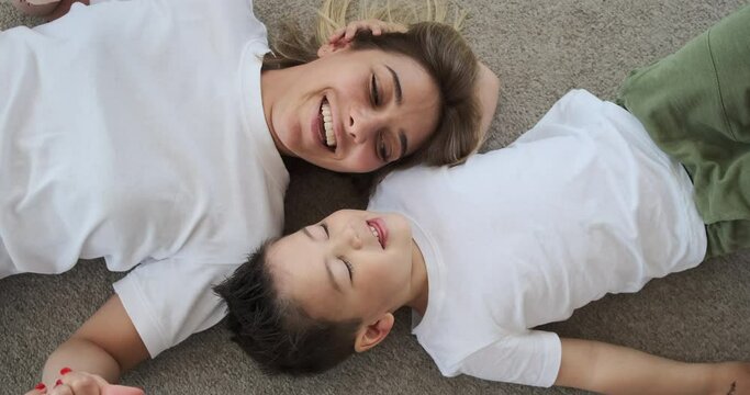 Loving mother and son singing song lying on the floor at home