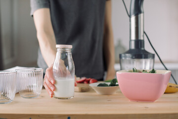 Woman preparing healthy smoothie with strawberries and banana. Homemade dessert with no added sugar.