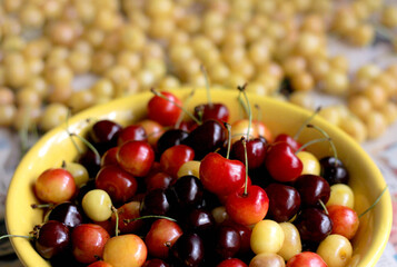 Yellow plate full of cherries on wooden table