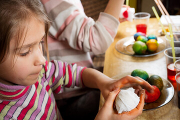 Close up video of hands of children using dye and painting on white boiled eggs while preparing for Easter
