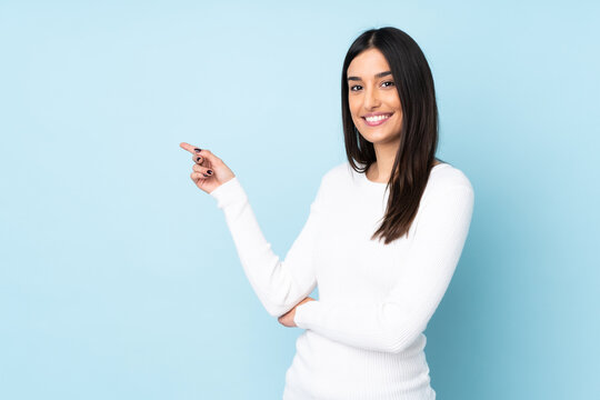 Young caucasian woman isolated on blue background pointing finger to the side